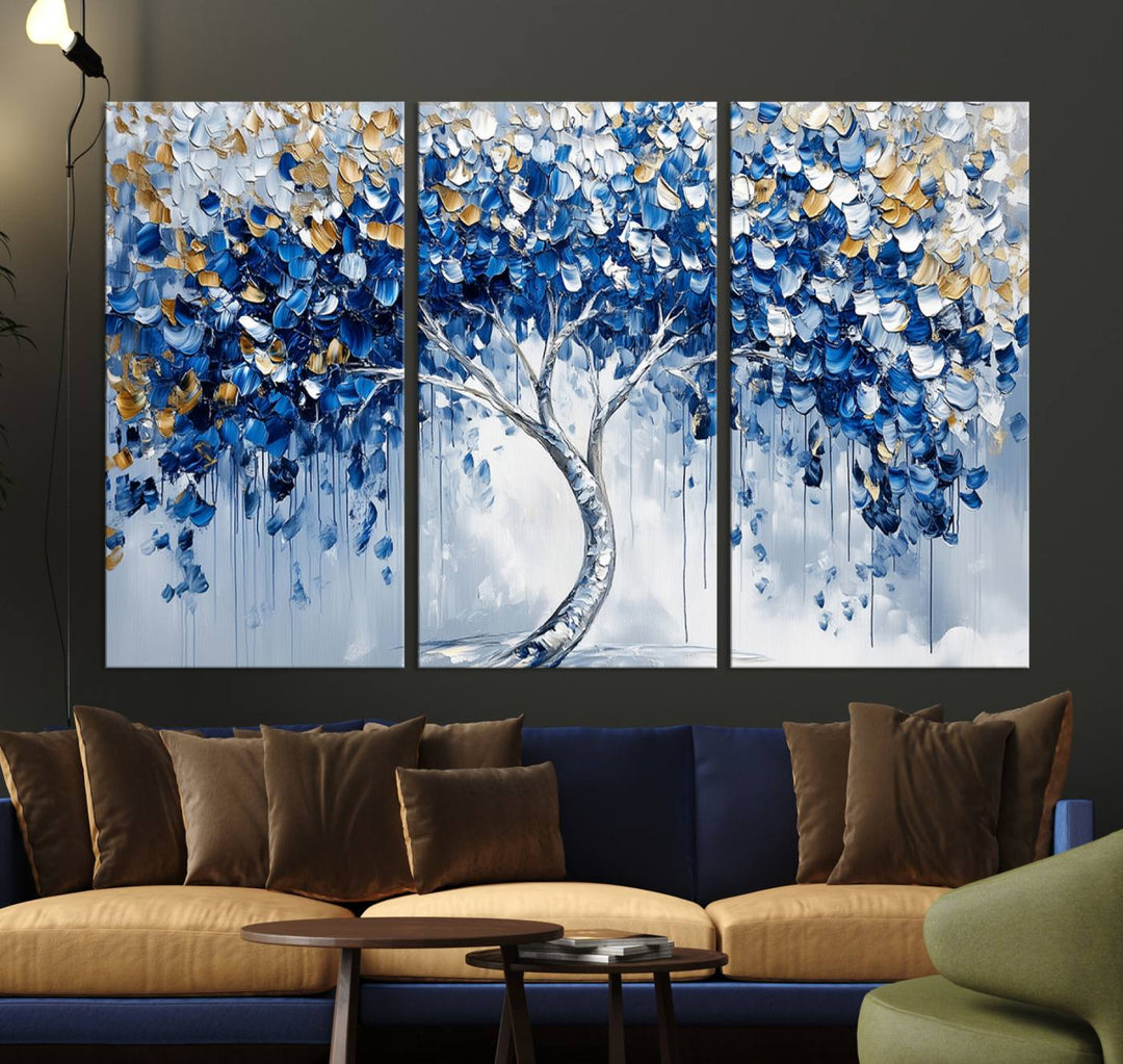 The Blue and Gold Abstract Tree Wall Art showcases a swirl trunk and features blue, silver, and gold leaves on a framed canvas print.