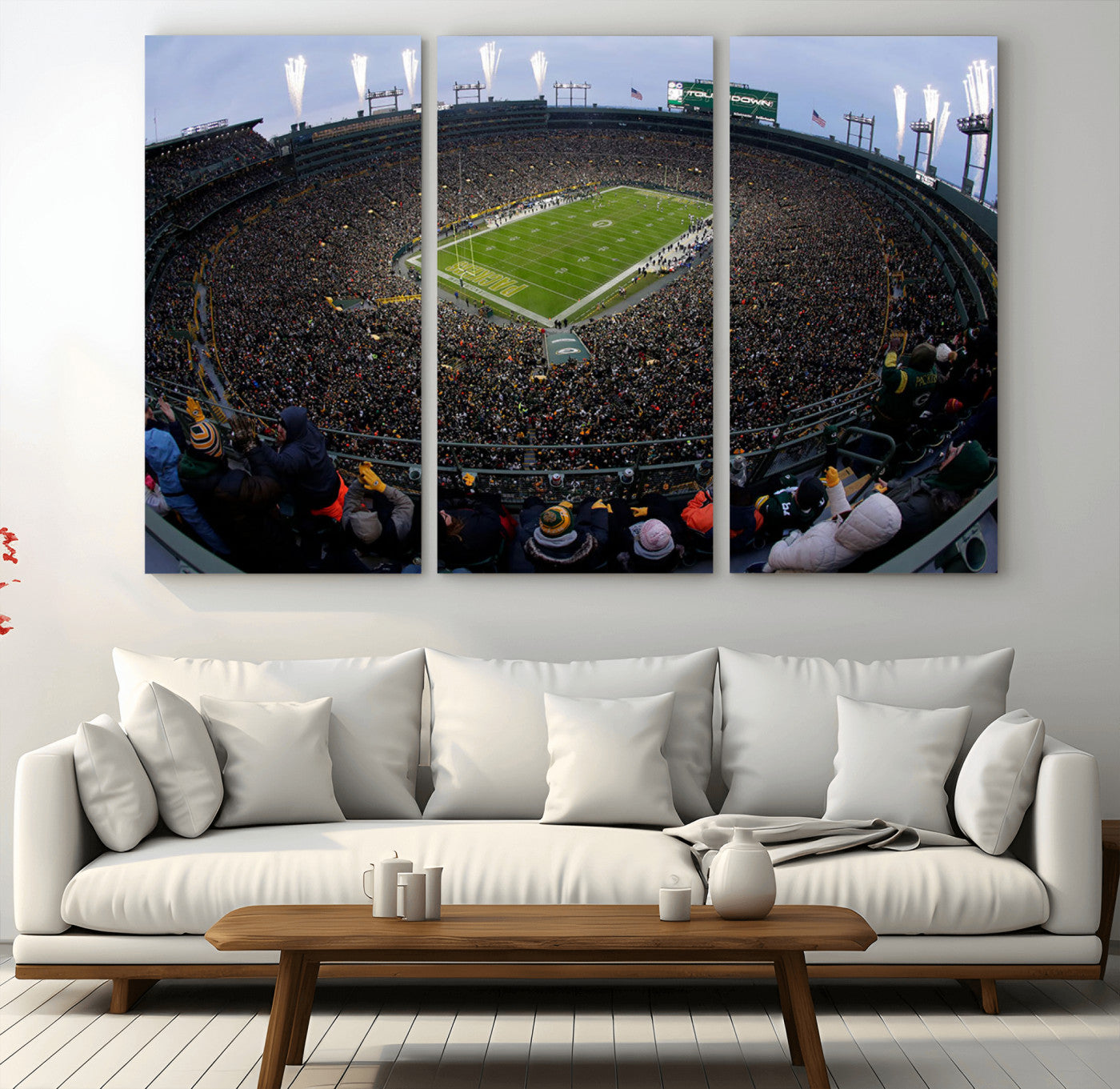 Wide fisheye view of a packed Lambeau Field stadium during an American football game. The crowd fills the stands, and fireworks are going off above the stadium lights. The scoreboard displays "Touchdown," and the field has "Packers" painted in the end zon