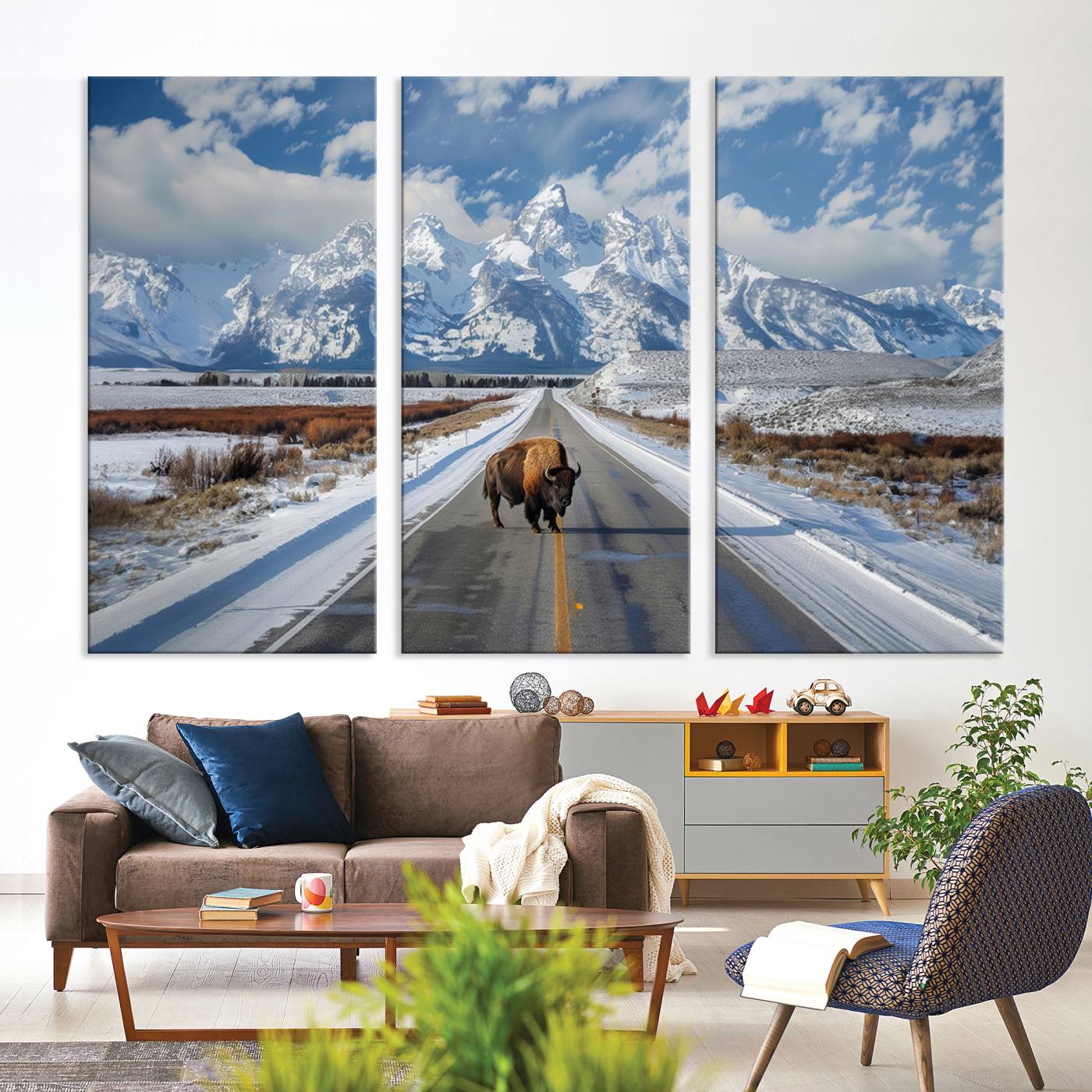 A powerful bison stands on a snow-dusted road beneath the towering peaks of the Grand Tetons, capturing the untamed beauty of America's winter wilderness.