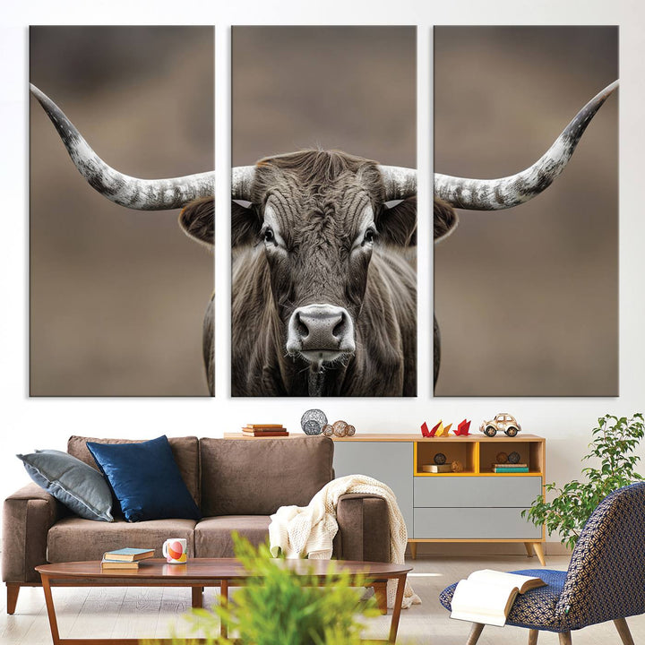 A close-up of a longhorn bull facing forward is featured in the Framed Texas Test-1, set against a blurred brown background.