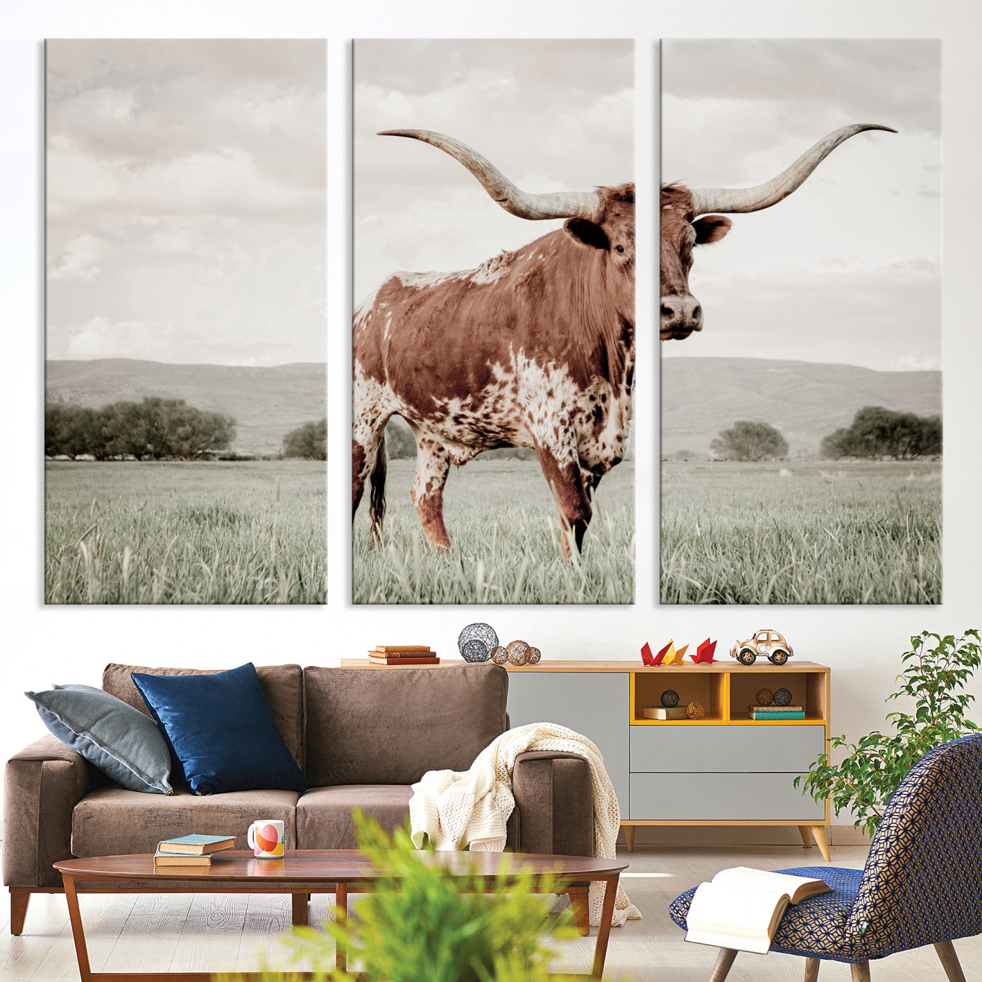 Canvas of a Texas longhorn standing in a grassy field with mountains in the background, ideal for rustic or country-style western wall decor.