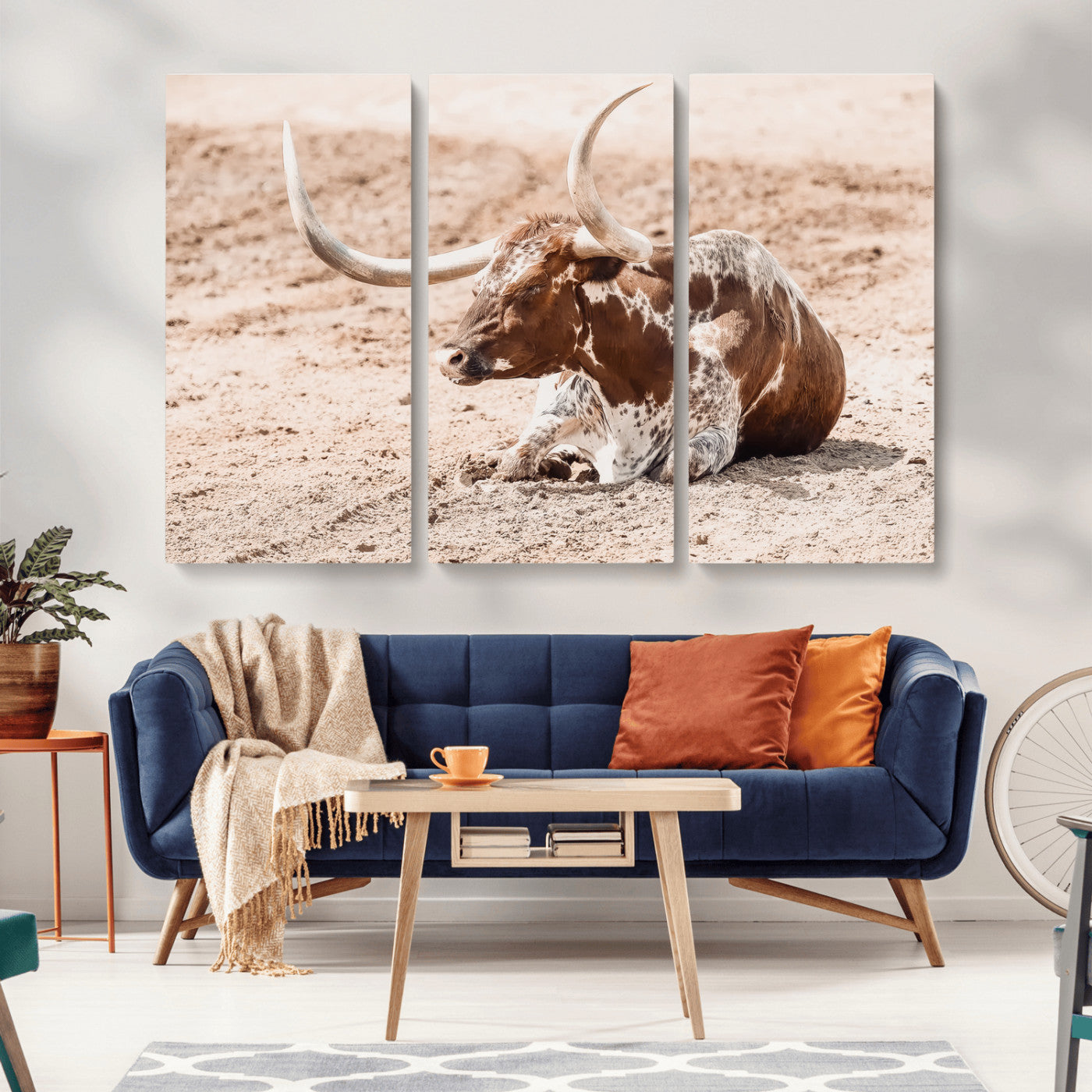 Texas Longhorn bull resting on dusty ground with warm tones, ideal for rustic western or farmhouse-themed wall decor.