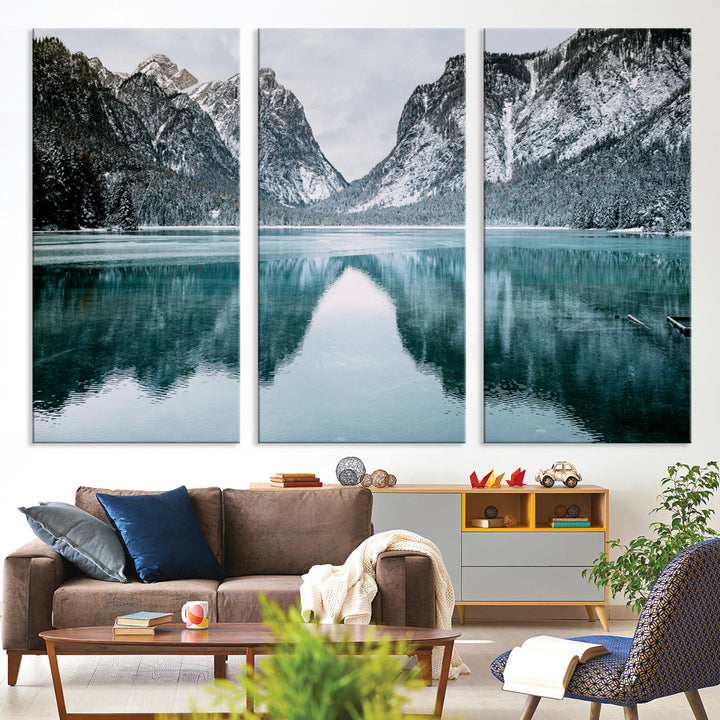 Crystal-clear alpine lake reflecting snow-covered mountains, surrounded by evergreen trees, creating a serene and tranquil winter landscape.