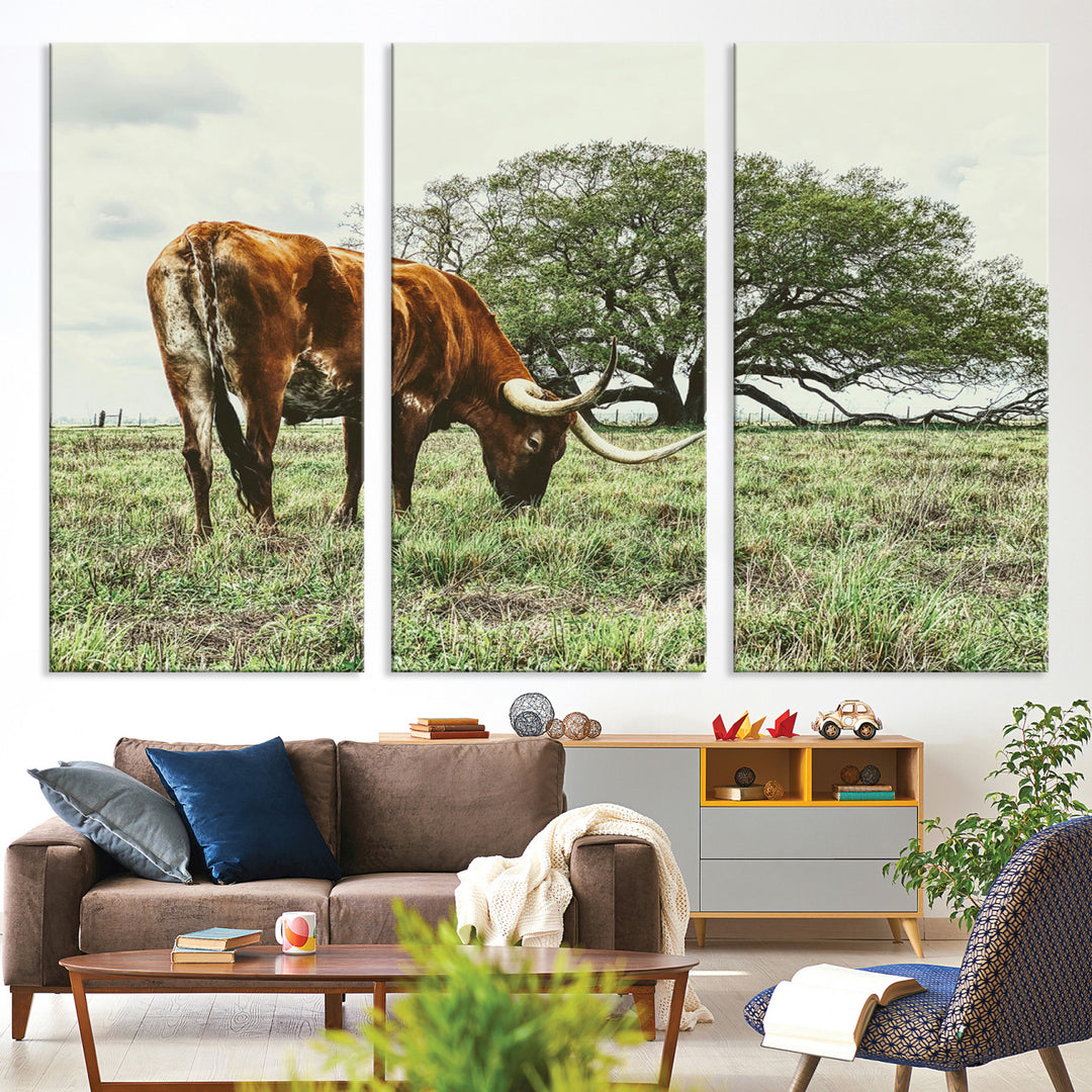 A Texas Longhorn grazing in a green pasture with a large tree in the background, evoking a rustic Western and farmhouse aesthetic.