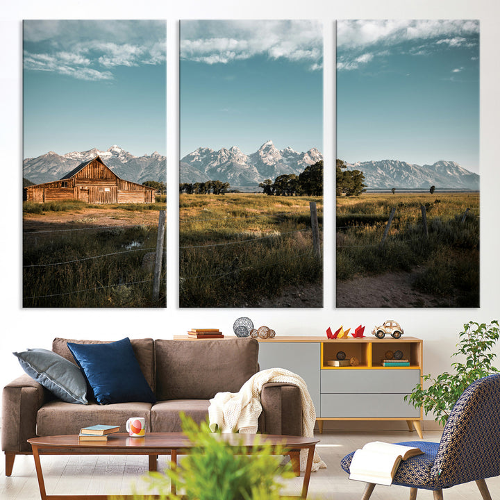 A rustic farmhouse with a wooden barn set against majestic mountain peaks under a soft blue sky, evoking peaceful countryside charm.