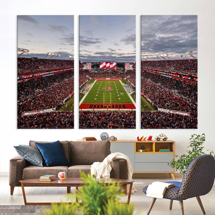 The wall art captures a stunning scene of Raymond James Stadium bathed in the warm hues of sunset. The sky, filled with clouds, provides a dramatic contrast to the vibrant lighting on the field, encapsulating the dynamic energy of a football game.