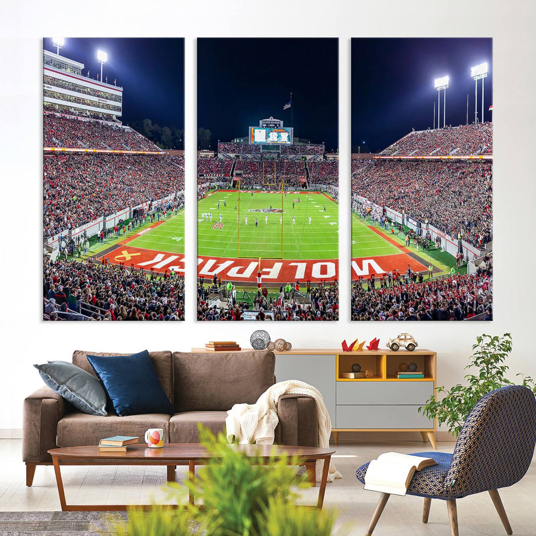 A NC State Wolfpack Football Team print of Carter-Finley Stadium at night features WOLFPACK illuminated brightly in the end zone grass.