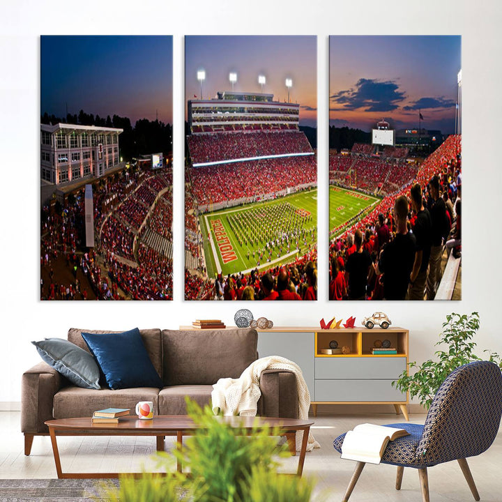 A print of a bustling Carter-Finley Stadium at dusk, featuring fans and a band, captures the essence of NC State Wolfpack football.