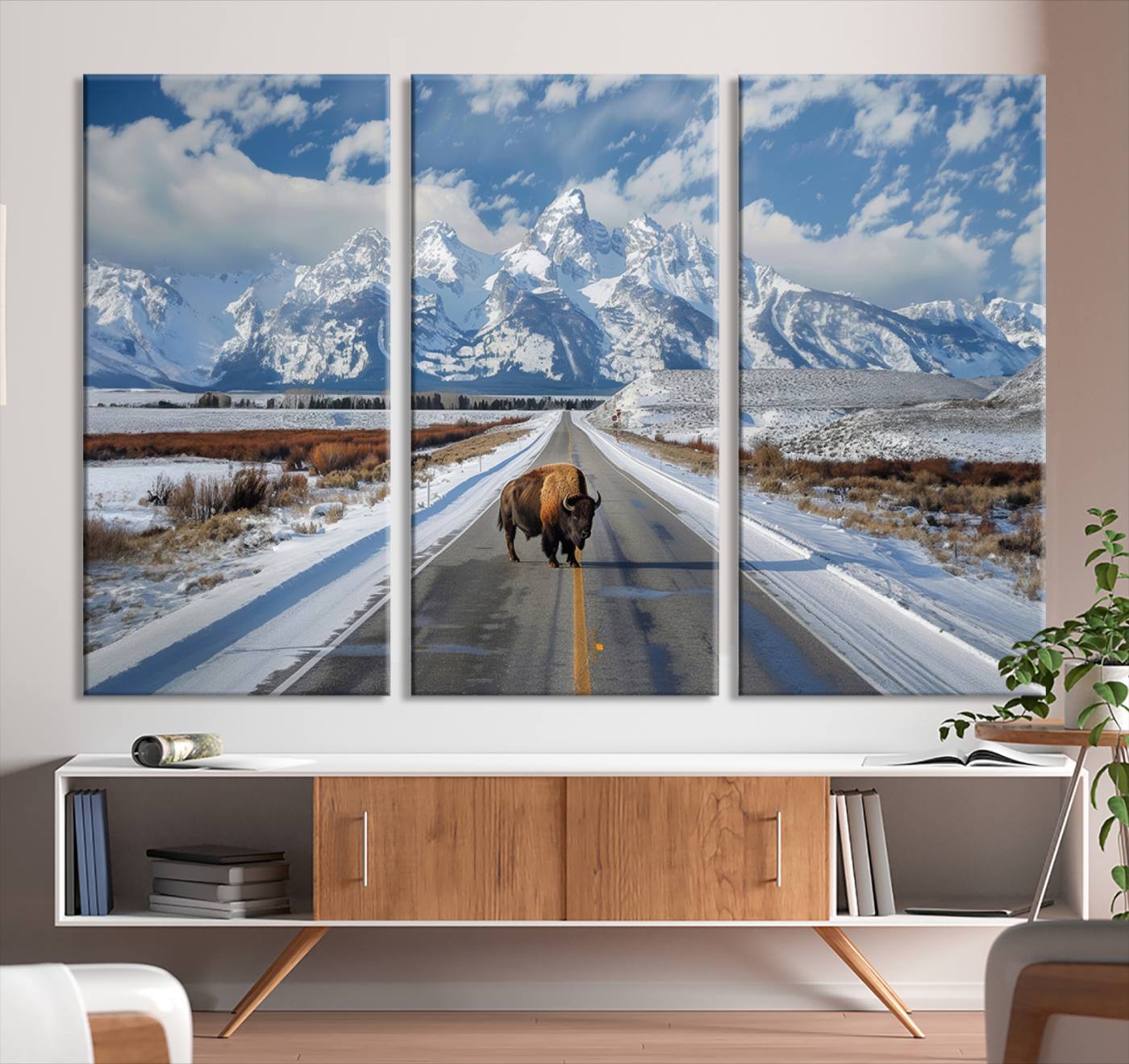 A powerful bison stands on a snow-dusted road beneath the towering peaks of the Grand Tetons, capturing the untamed beauty of America's winter wilderness.