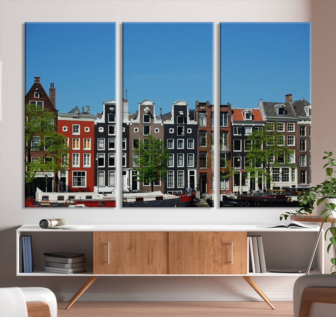 The Amsterdam City Wall Art Canvas Print showcases colorful traditional canal houses and boats set against a clear blue sky.