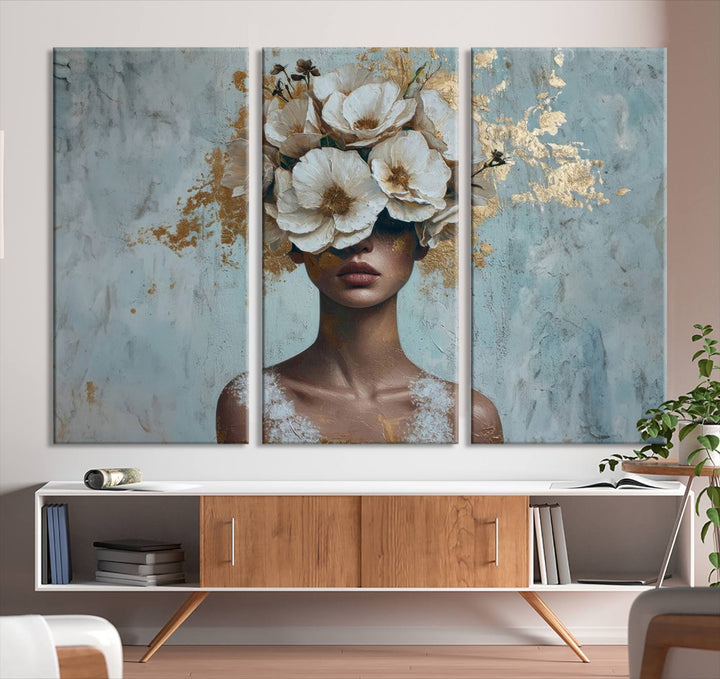 The Golden Petal Silhouette Woman Wall Art Canvas Print, a large 3-panel canvas with a textured gold floral design, serves as a luxurious centerpiece in modern glam settings. The artwork depicts a woman with flowers over her eyes against a textured background and hangs elegantly.