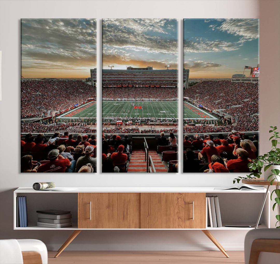 The living room features a stunning triptych of Lincoln Memorial Stadium wall art canvas print, celebrating the University of Nebraska Cornhuskers football team. This piece serves as captivating wall art, showcasing a gallery-quality finish.