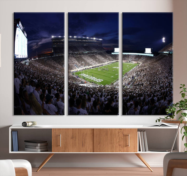 A packed football stadium at night, with bright lights and fans in white, depicted in a Michigan State Spartans Stadium wall art.