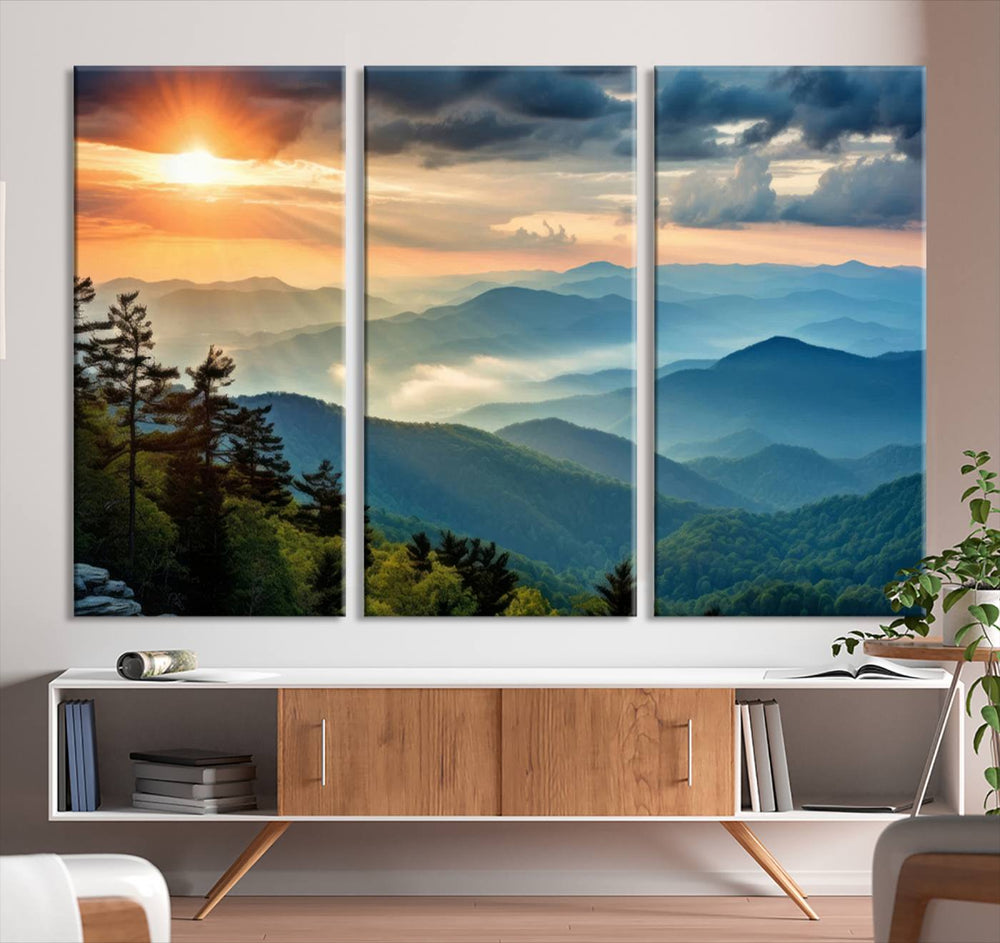 The wall art, titled Sunrise Over Mountain Range, is a canvas print that beautifully depicts layers of hills, scattered trees, and a partly cloudy sky.