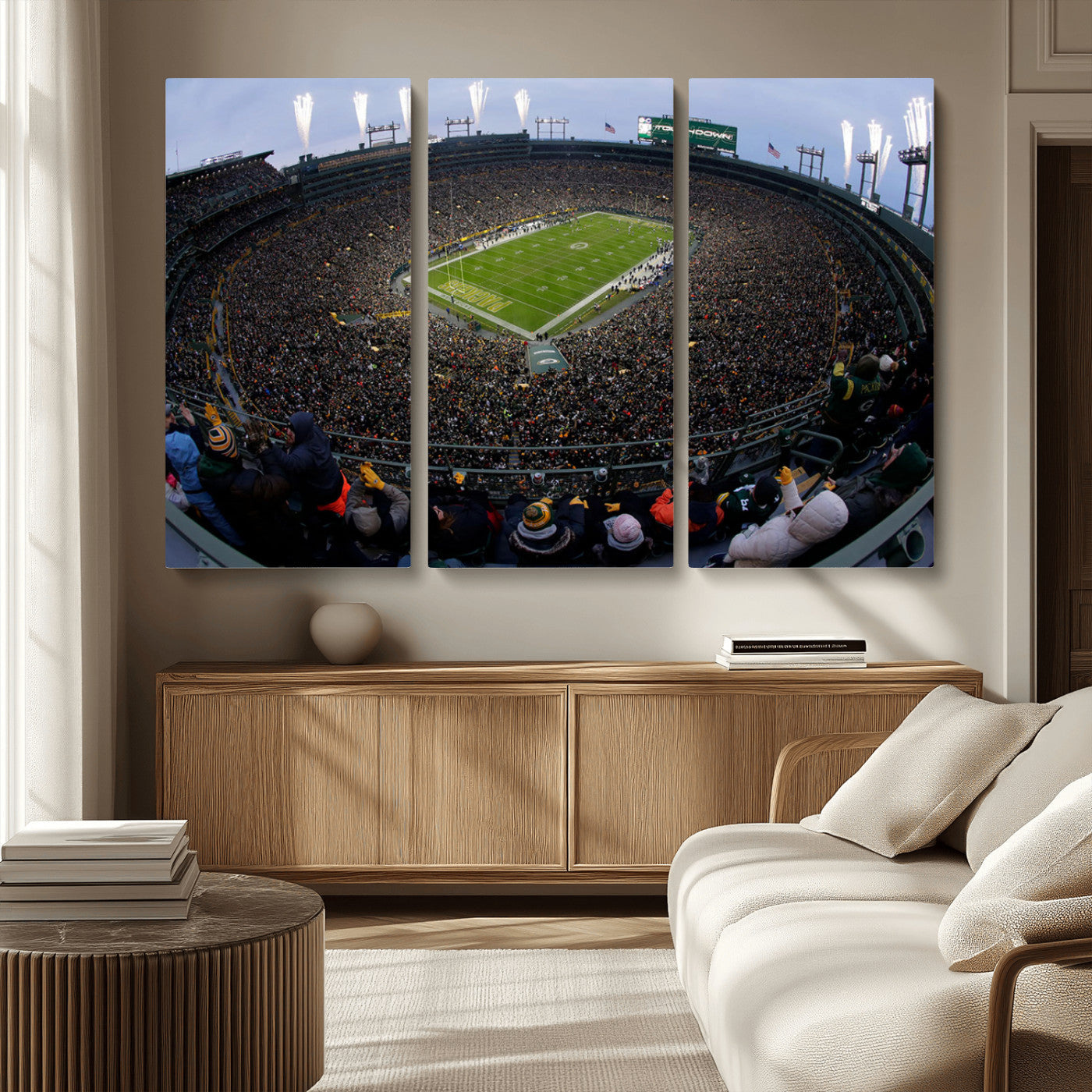 Wide fisheye view of a packed Lambeau Field stadium during an American football game. The crowd fills the stands, and fireworks are going off above the stadium lights. The scoreboard displays "Touchdown," and the field has "Packers" painted in the end zon