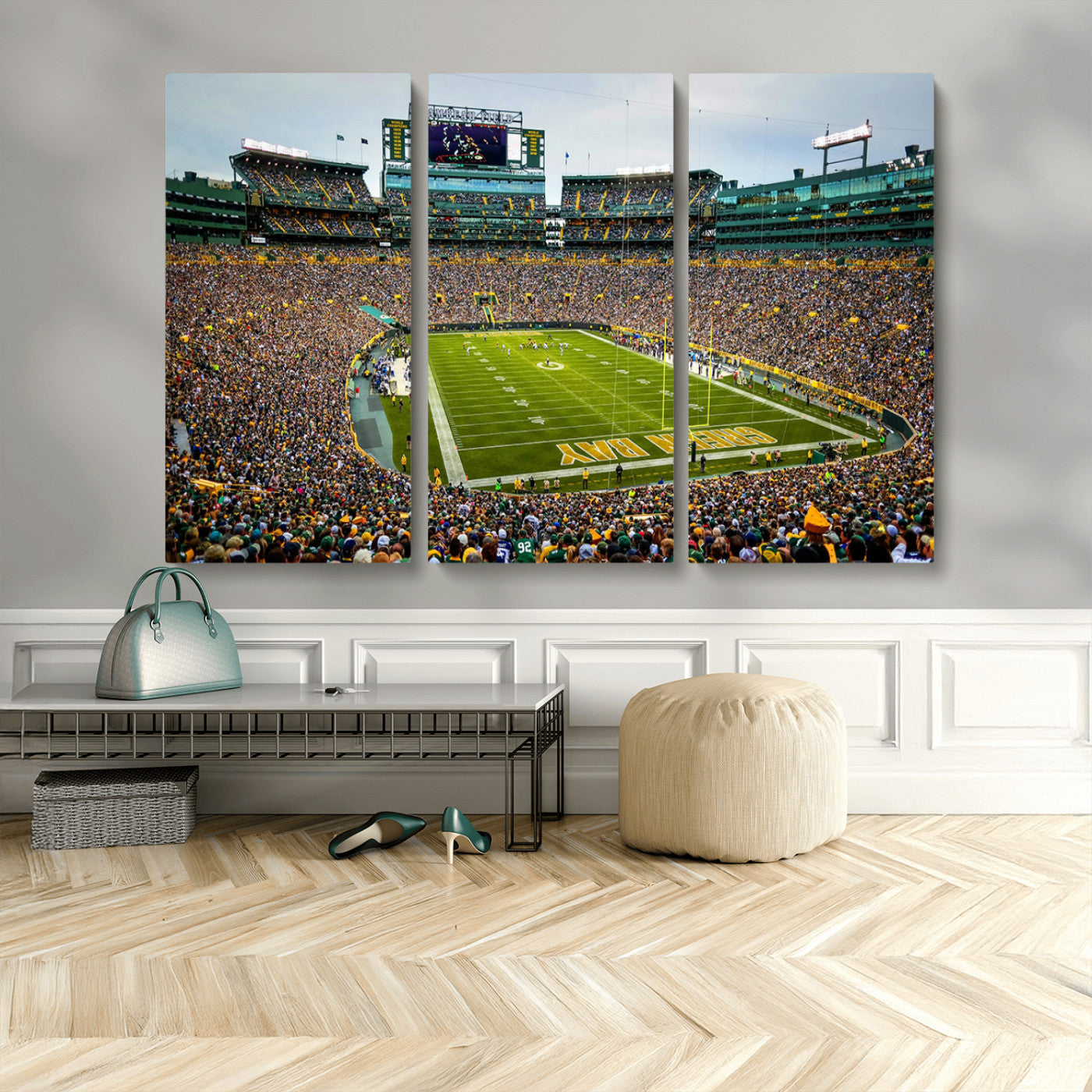 Packed football stadium with thousands of fans watching an American football game on a well-maintained field. The scoreboard displays "Lambeau Field," and players are lined up on the field. The stadium is surrounded by multiple tiers of seating filled wit