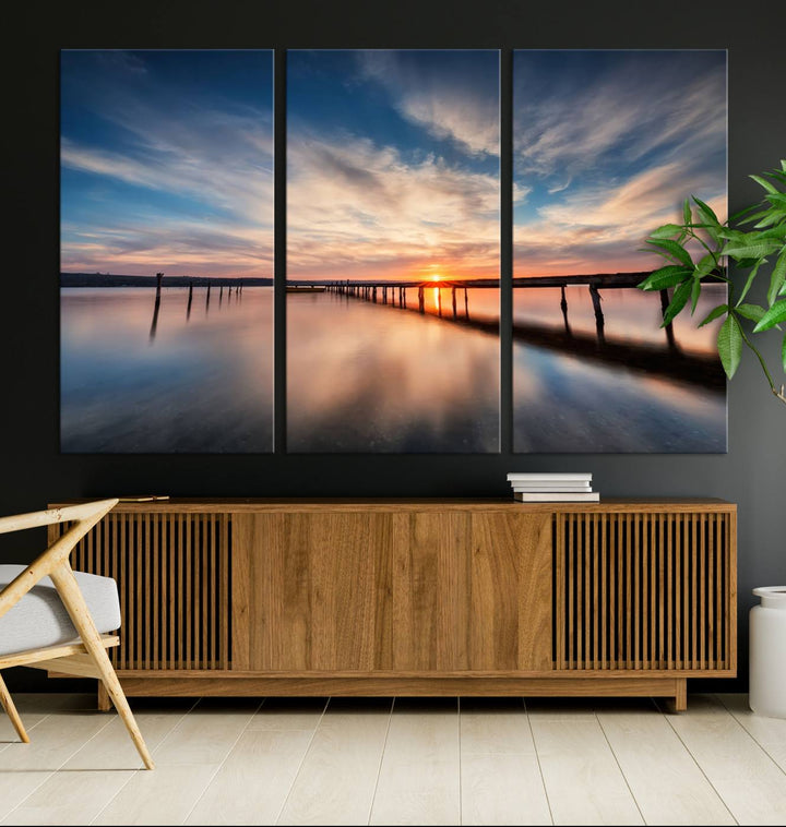 The tranquil sunset casting its glow over a peaceful lake with a long wooden pier captures the essence of coastal allure. The soft clouds mirrored in the water beautifully evoke the ambiance provided by the Sunset Pier Giclee Canvas Wall Art, a masterpiece designed for modern home decor and reminiscent of minimalist art.