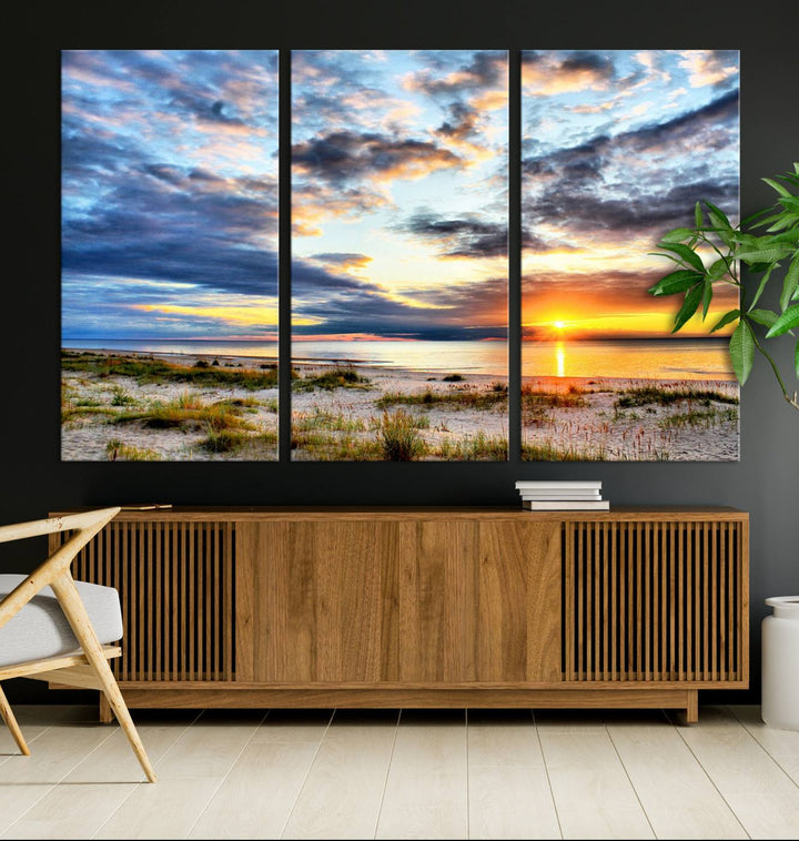 The Sunset On The Ocean canvas wall art features a beautiful beach sunset with grass and clouds.