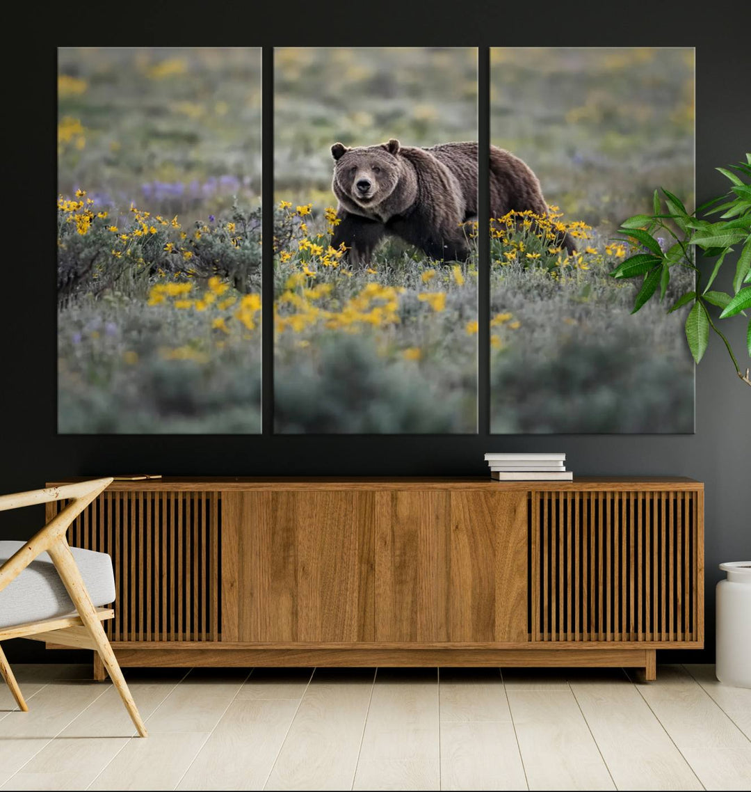 The "Grizzly 399 in Wild Flowers Wall Art Canvas Print" features a grizzly bear strolling through a field of yellow and purple flowers, beautifully showcased as a triptych. This handcrafted piece, proudly made in the USA, adds charm and sophistication to your space.