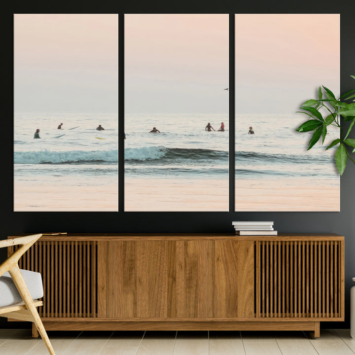 Dreamy photo of surfers waiting on soft pastel waves under a pink sunset sky, ideal for soft coastal minimalist or serene ocean-themed home decor.