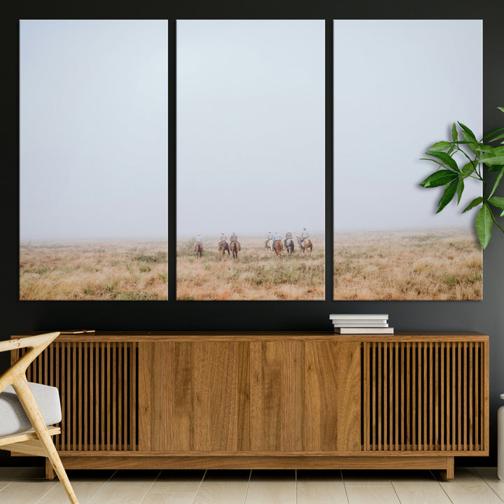 A group of horseback riders moving through a fog-shrouded field, evoking a calm Western scene with golden grasses and soft horizons.