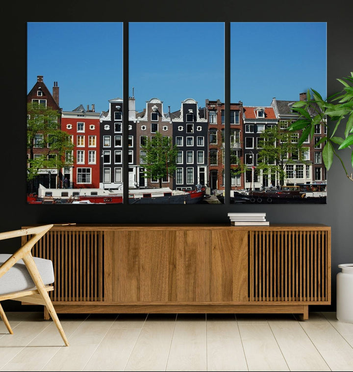 The Amsterdam City Wall Art Canvas Print showcases colorful traditional canal houses and boats set against a clear blue sky.