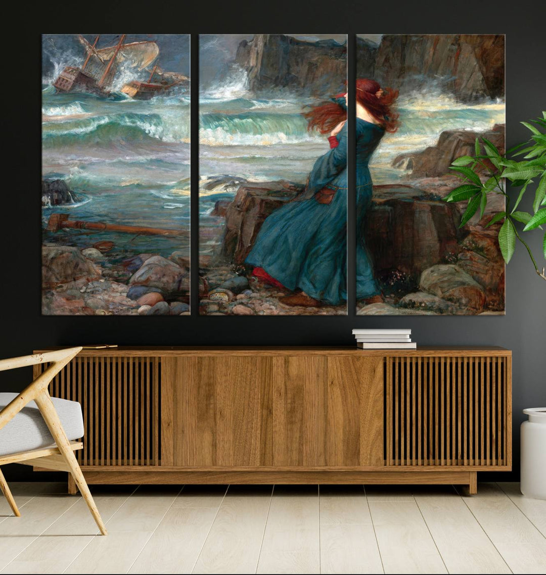 The Miranda by the Shore Wall Art Canvas Print depicts a woman in a blue dress standing by the sea, watching a shipwreck.