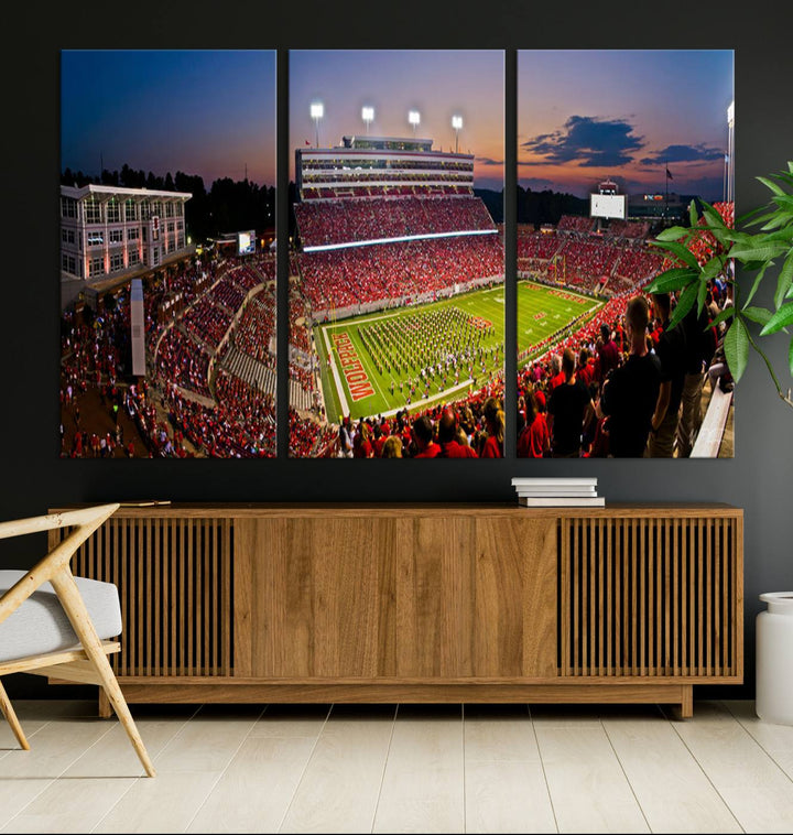 A print of a bustling Carter-Finley Stadium at dusk, featuring fans and a band, captures the essence of NC State Wolfpack football.