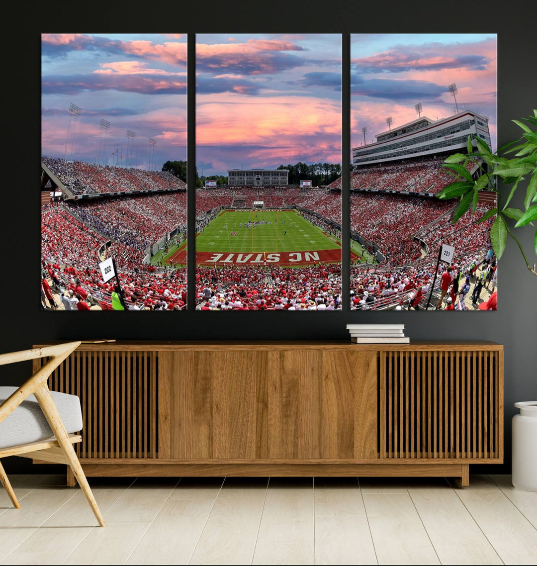 The wall art captures an NC State Wolfpack game under a vibrant sunset on triple canvas.