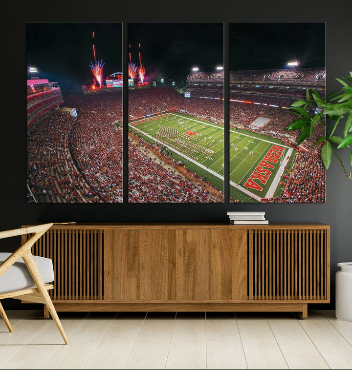 The University of Nebraska Cornhuskers Football Team Print, featuring Lincoln Memorial Stadium in a vibrant triptych canvas with fireworks above and a gallery-quality finish, is elegantly displayed.