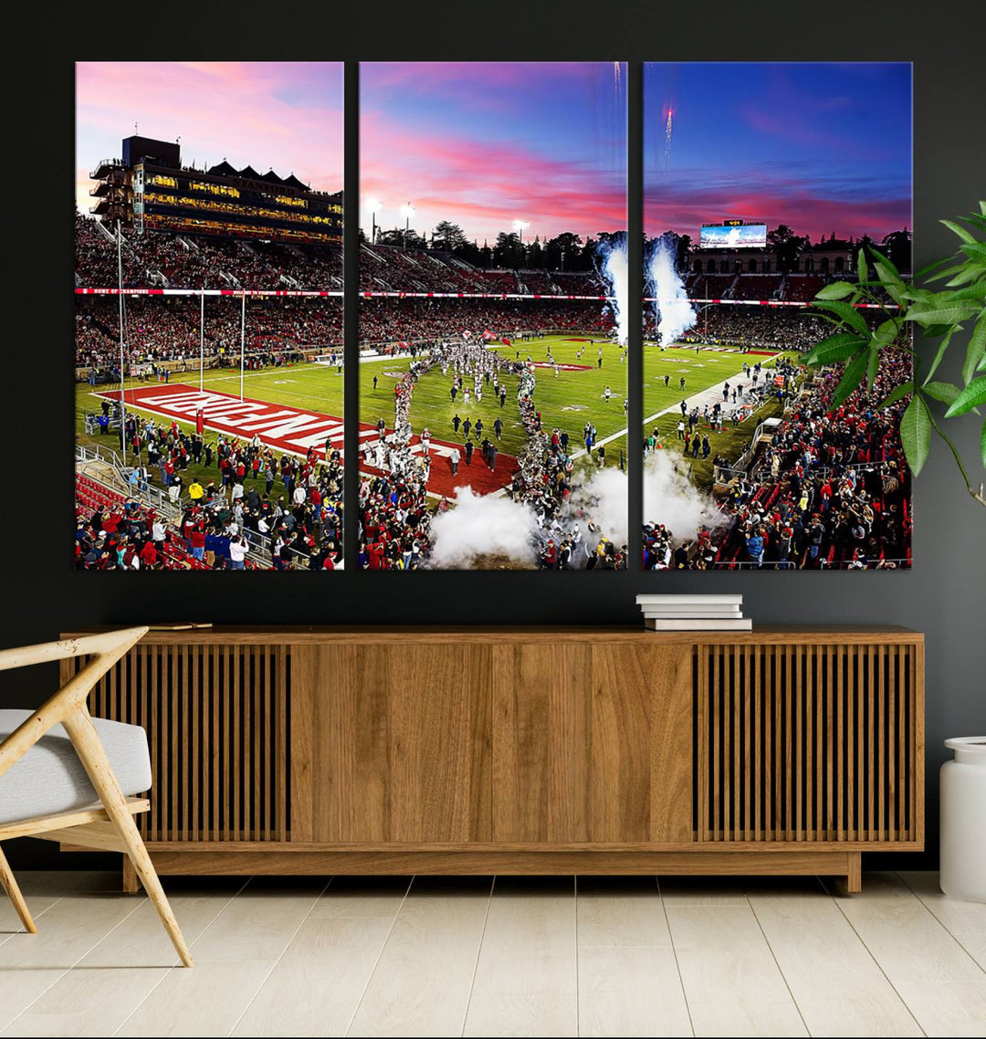 The wall art features a canvas print of the Stanford Cardinal football team, capturing players, fireworks, and smoke against the backdrop of a sunset at Stanford Stadium.