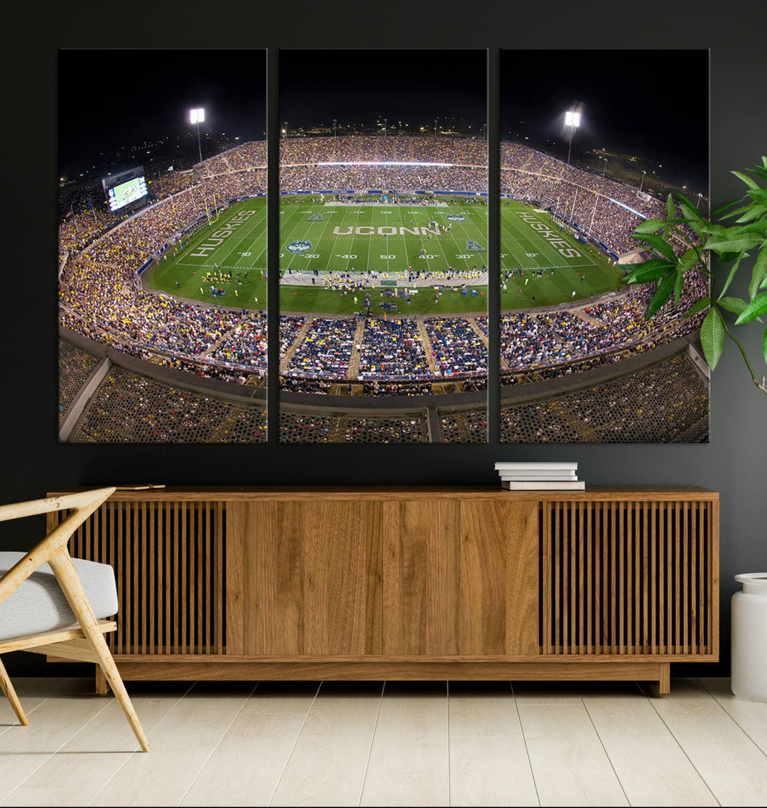 A large football stadium at night, featuring the UCONN Huskies, is depicted on the East Hartford Pratt & Whitney Stadium Wall Art Canvas Print.