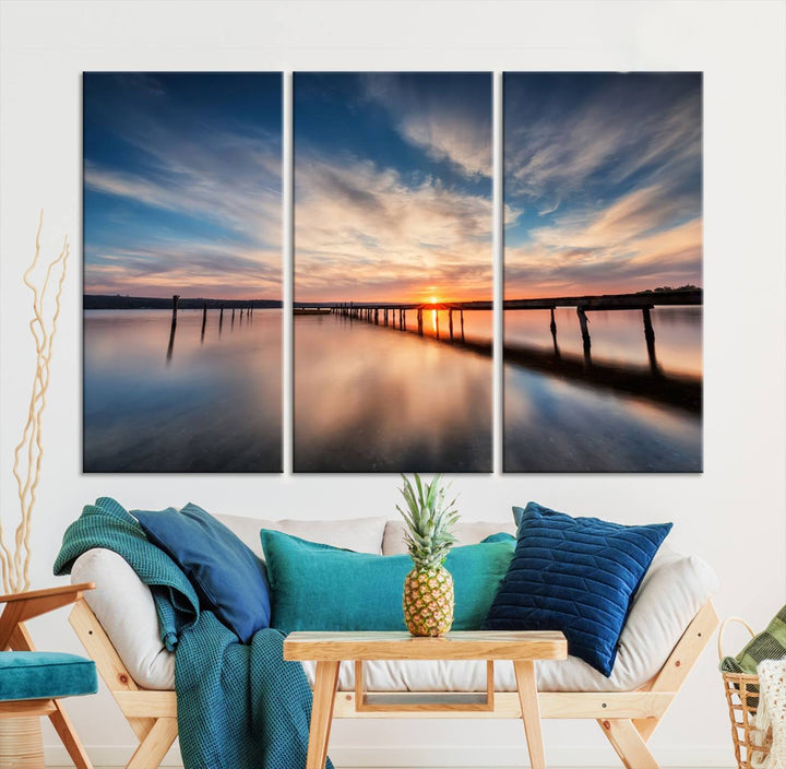 The tranquil sunset casting its glow over a peaceful lake with a long wooden pier captures the essence of coastal allure. The soft clouds mirrored in the water beautifully evoke the ambiance provided by the Sunset Pier Giclee Canvas Wall Art, a masterpiece designed for modern home decor and reminiscent of minimalist art.