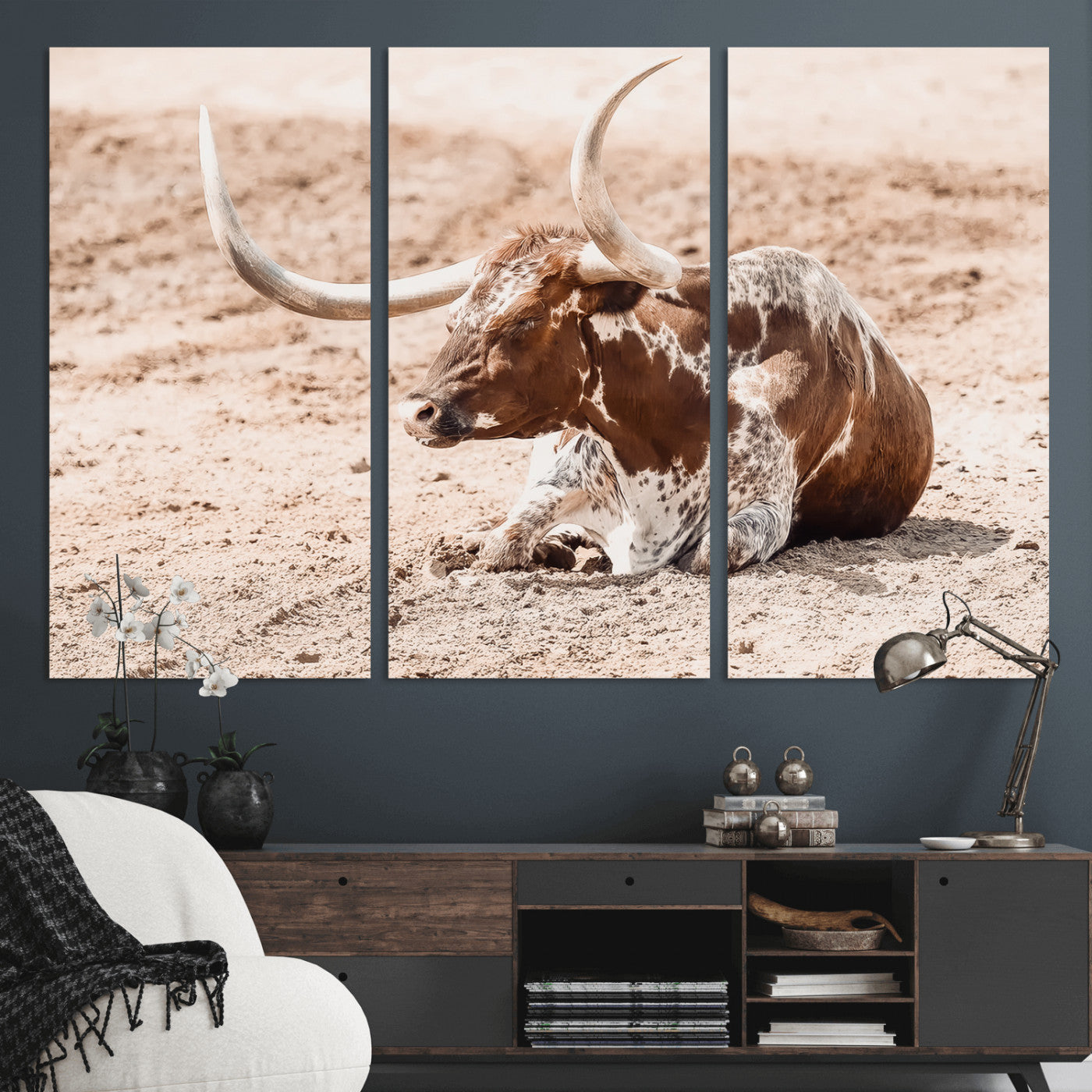 Texas Longhorn bull resting on dusty ground with warm tones, ideal for rustic western or farmhouse-themed wall decor.