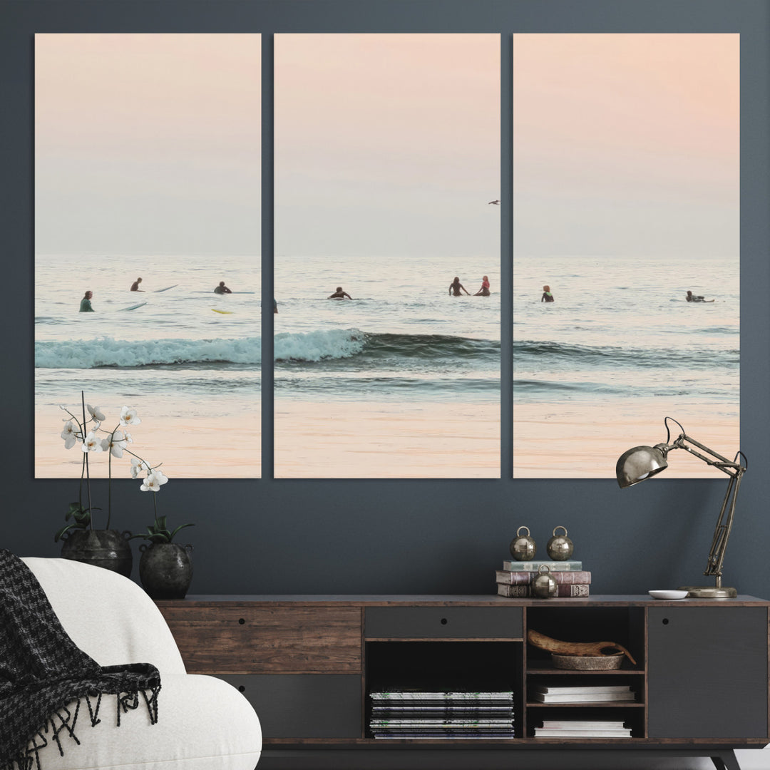 Dreamy photo of surfers waiting on soft pastel waves under a pink sunset sky, ideal for soft coastal minimalist or serene ocean-themed home decor.