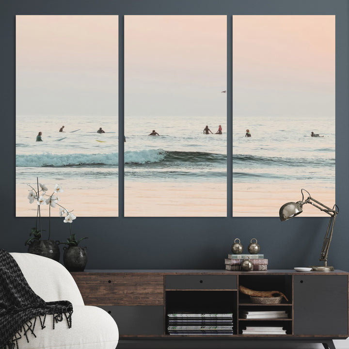 Dreamy photo of surfers waiting on soft pastel waves under a pink sunset sky, ideal for soft coastal minimalist or serene ocean-themed home decor.