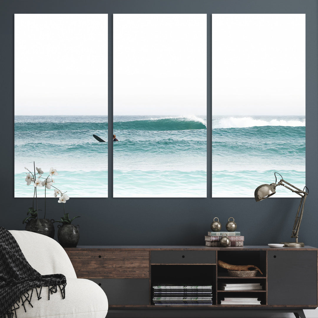 Minimalist photo of a lone surfer on calm aqua waves under bright sky, perfect for Scandinavian coastal or serene ocean-inspired home decor.
