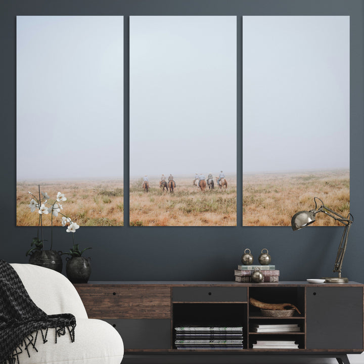 A group of horseback riders moving through a fog-shrouded field, evoking a calm Western scene with golden grasses and soft horizons.