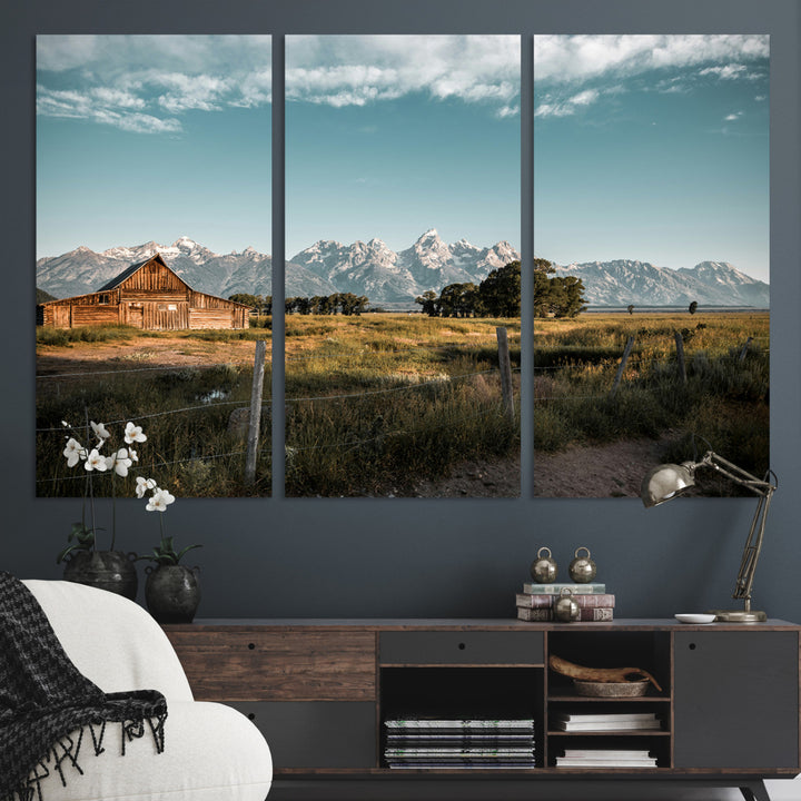 A rustic farmhouse with a wooden barn set against majestic mountain peaks under a soft blue sky, evoking peaceful countryside charm.