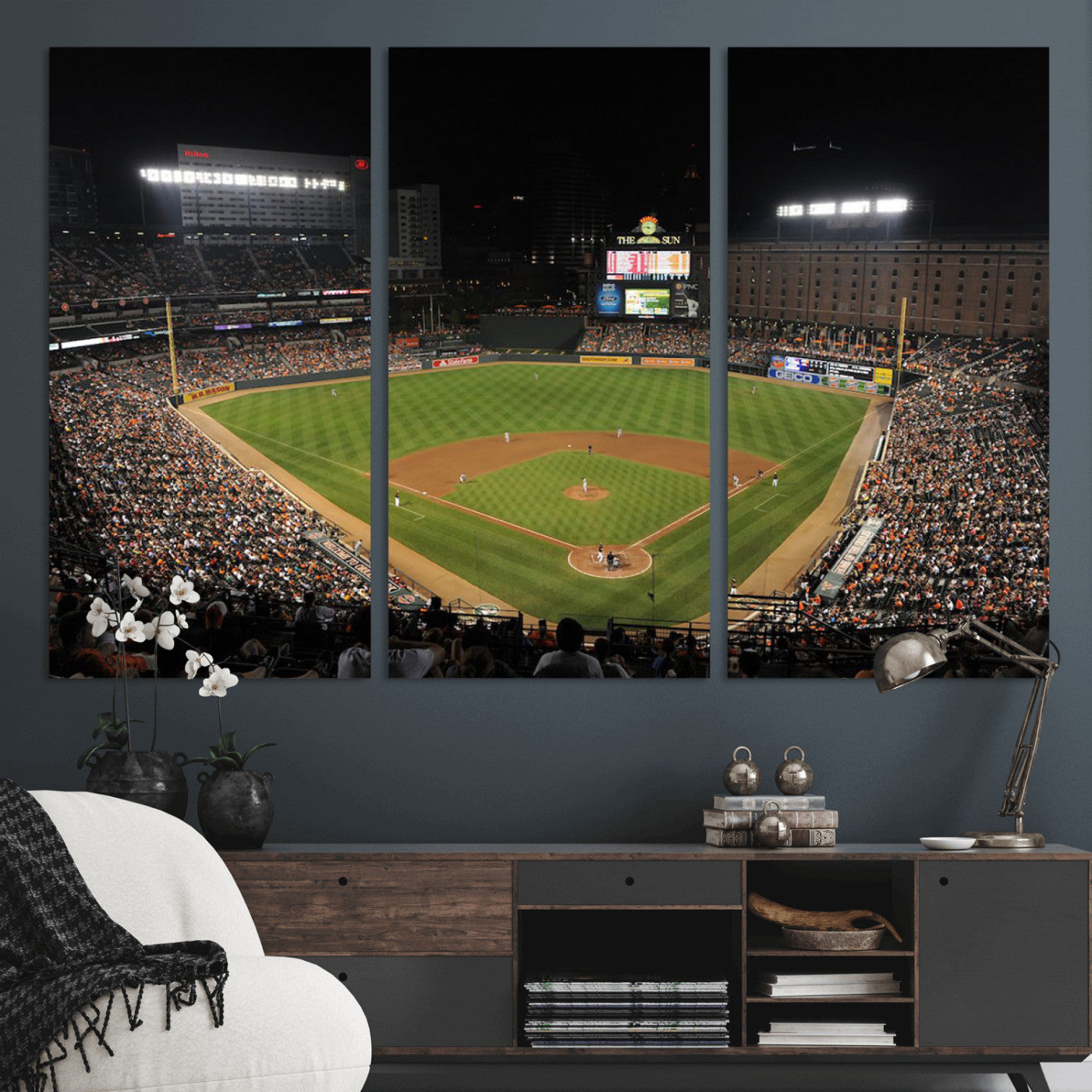 Aerial view of a baseball stadium at night with the field illuminated by stadium lights, players on the field, and a large crowd of spectators in the stands.