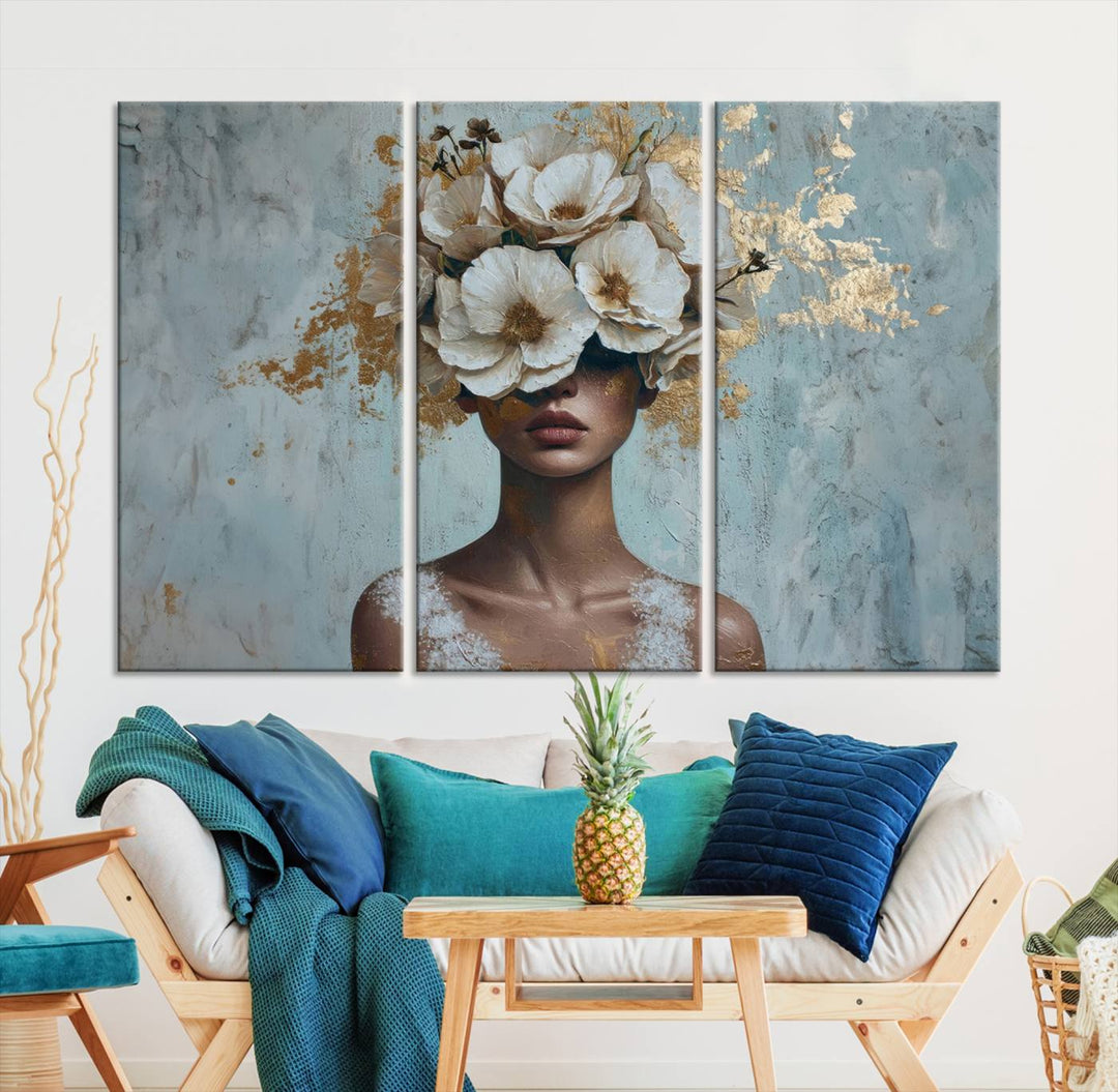 The Golden Petal Silhouette Woman Wall Art Canvas Print, a large 3-panel canvas with a textured gold floral design, serves as a luxurious centerpiece in modern glam settings. The artwork depicts a woman with flowers over her eyes against a textured background and hangs elegantly.