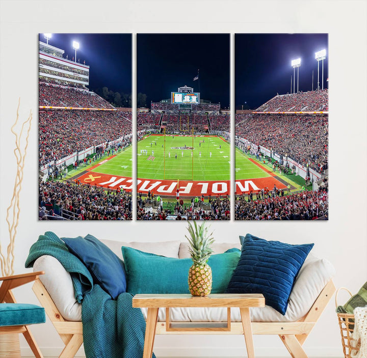 A NC State Wolfpack Football Team print of Carter-Finley Stadium at night features WOLFPACK illuminated brightly in the end zone grass.