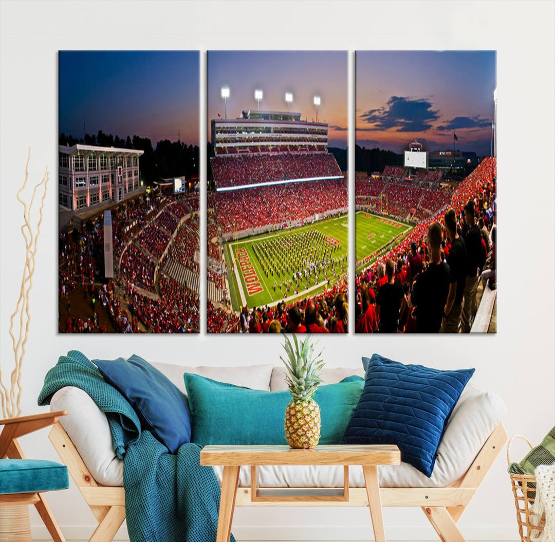 A print of a bustling Carter-Finley Stadium at dusk, featuring fans and a band, captures the essence of NC State Wolfpack football.