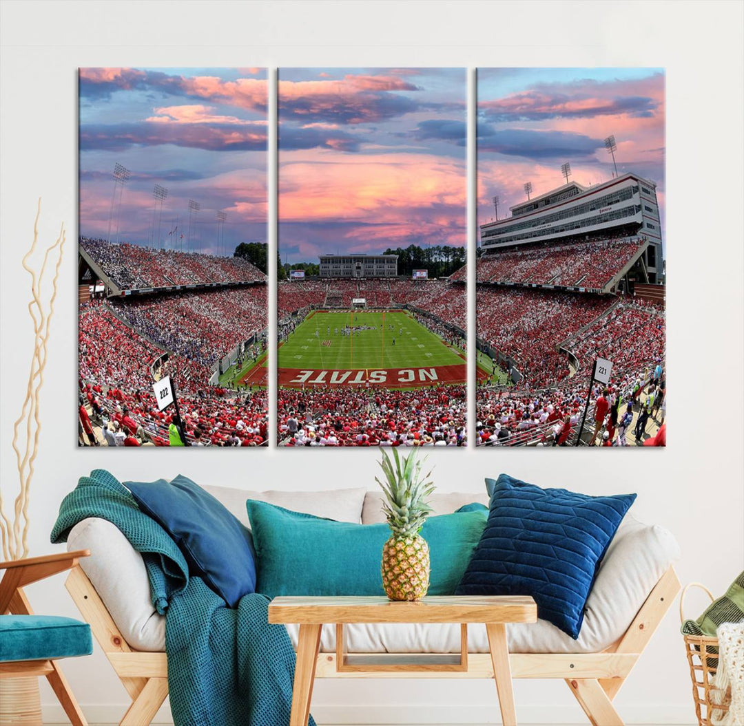 The wall art captures an NC State Wolfpack game under a vibrant sunset on triple canvas.