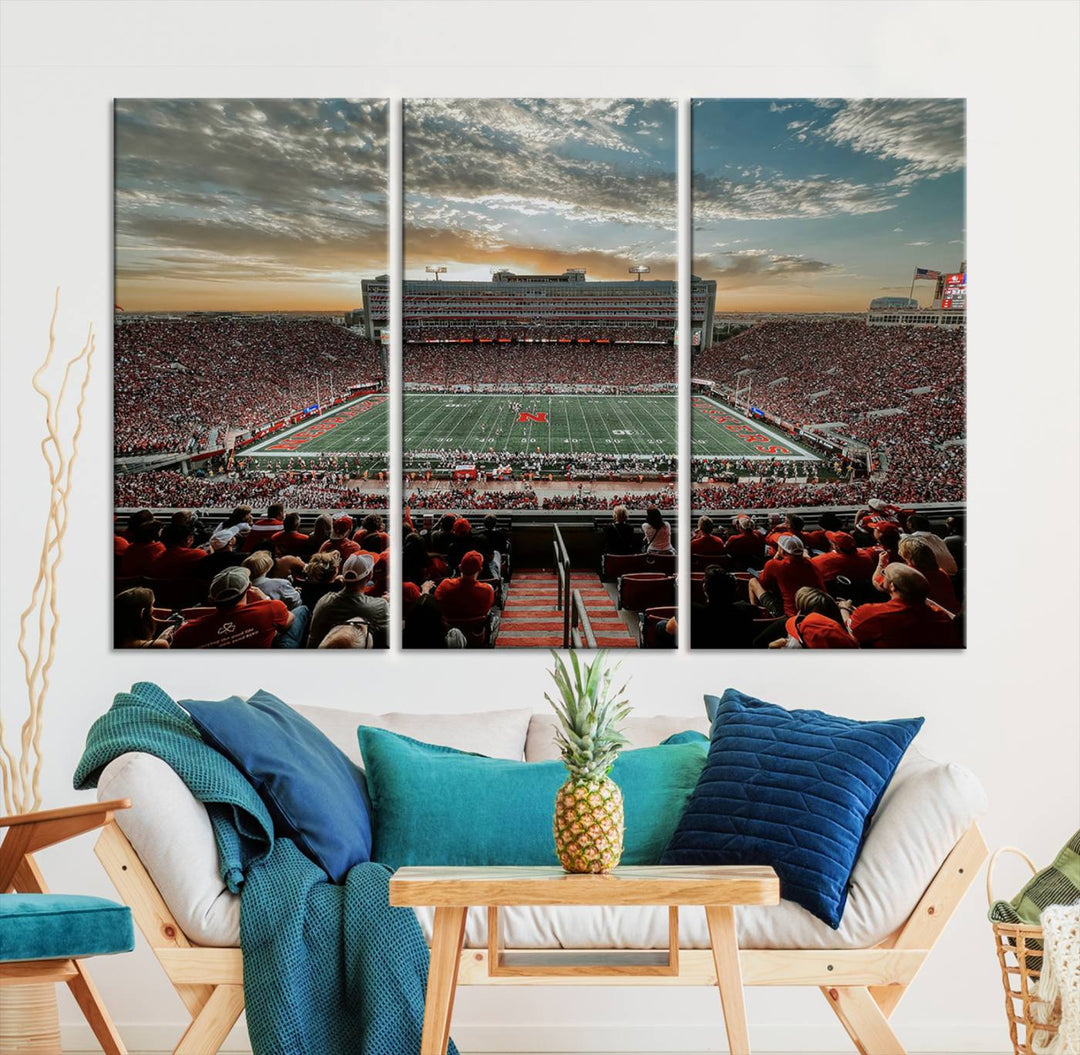 The living room features a stunning triptych of Lincoln Memorial Stadium wall art canvas print, celebrating the University of Nebraska Cornhuskers football team. This piece serves as captivating wall art, showcasing a gallery-quality finish.