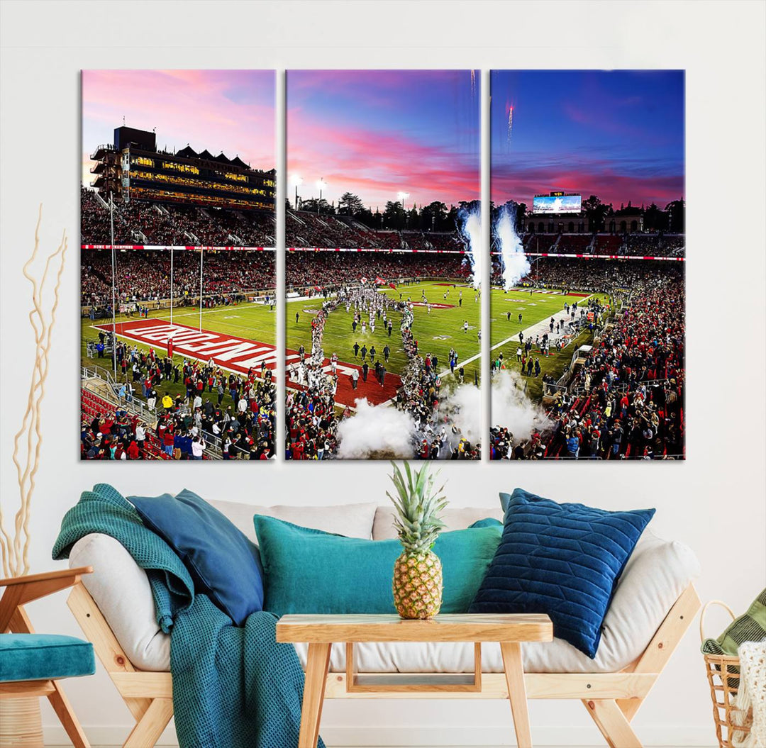 The wall art features a canvas print of the Stanford Cardinal football team, capturing players, fireworks, and smoke against the backdrop of a sunset at Stanford Stadium.