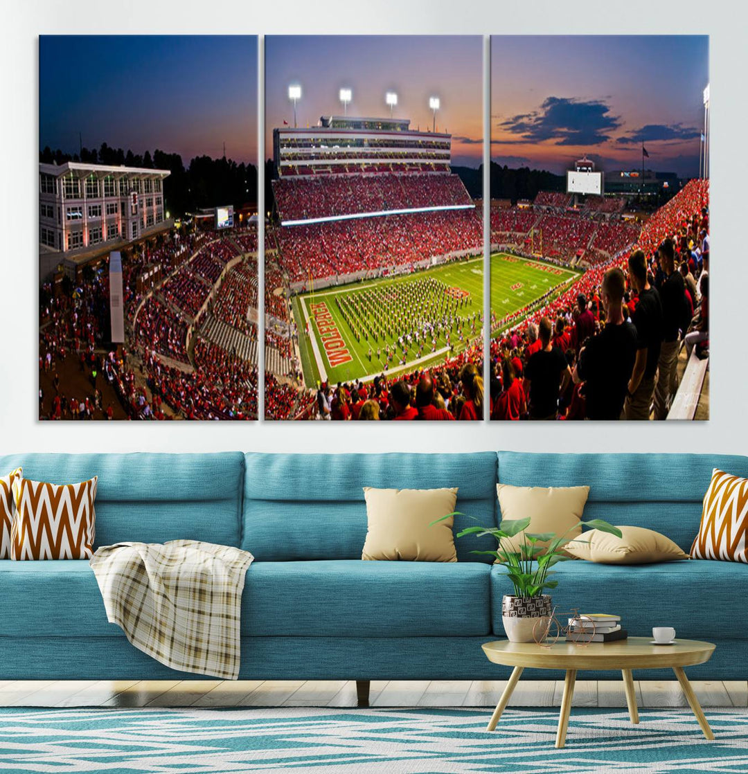 A print of a bustling Carter-Finley Stadium at dusk, featuring fans and a band, captures the essence of NC State Wolfpack football.