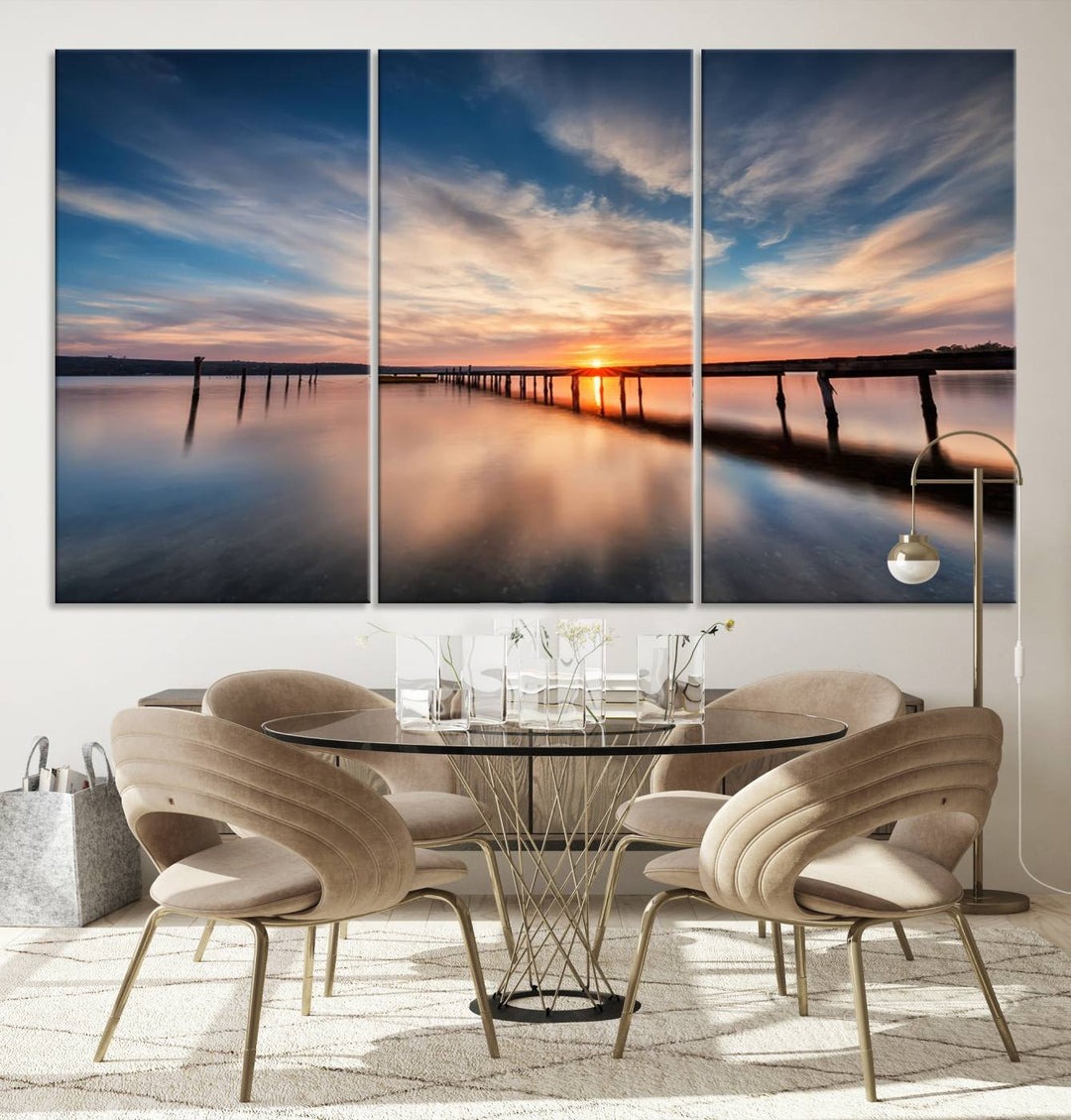 The tranquil sunset casting its glow over a peaceful lake with a long wooden pier captures the essence of coastal allure. The soft clouds mirrored in the water beautifully evoke the ambiance provided by the Sunset Pier Giclee Canvas Wall Art, a masterpiece designed for modern home decor and reminiscent of minimalist art.