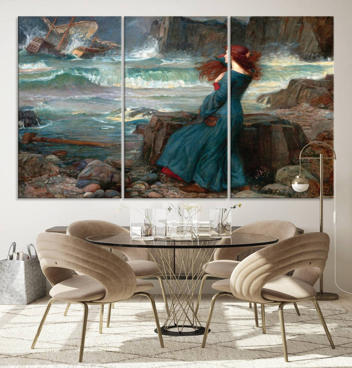 The Miranda by the Shore Wall Art Canvas Print depicts a woman in a blue dress standing by the sea, watching a shipwreck.