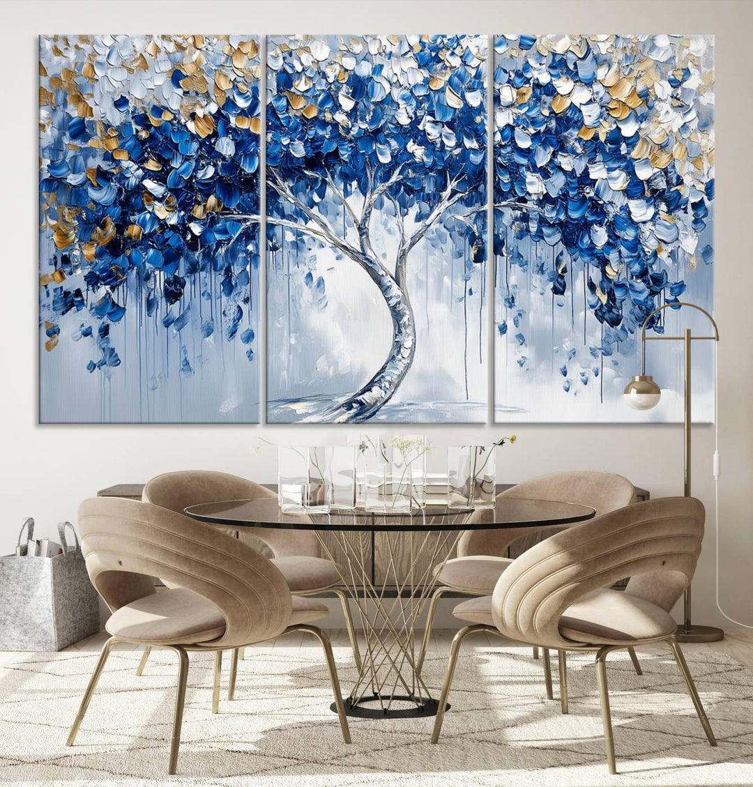 The Blue and Gold Abstract Tree Wall Art showcases a swirl trunk and features blue, silver, and gold leaves on a framed canvas print.